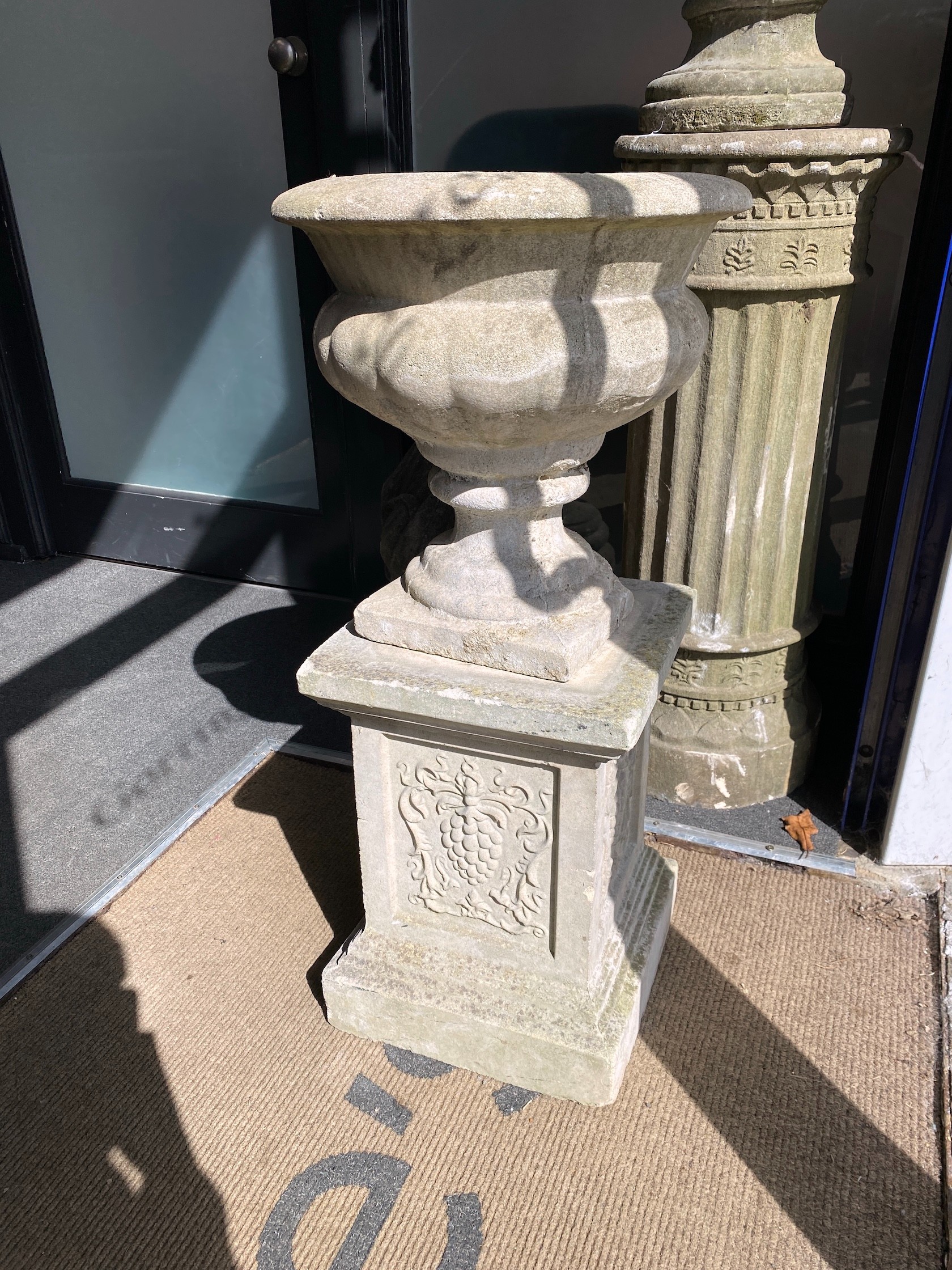 A pair of reconstituted stone campana garden urns on a near pair of square pedestals, larger height 86cm